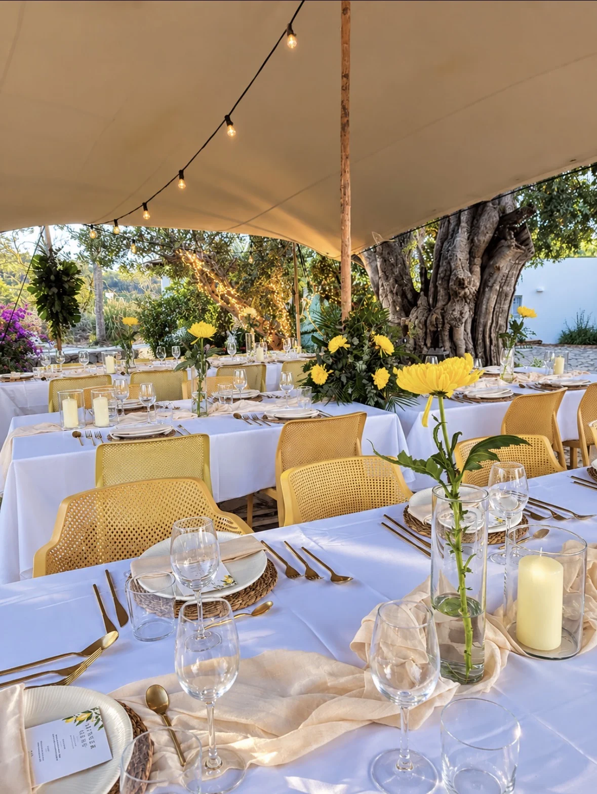 An event table styled with flowers, candles and yellow accents